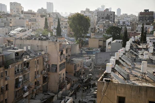 16일 이스라엘 텔아비브 인근 브네이브라크에서 구조대원, 경찰, 군인들이 이란의 미사일 공격으로 초토화된 현장을 조사하고 있다. 브네이브라크=AP 연합뉴스