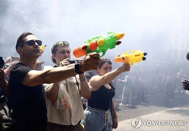 관광객과 상점을 향해 물총을 발사하는 시위대 (바르셀로나 로이터=연합뉴스) 과잉 관광에 반대하는 바르셀로나 시위대가 15일(현지시간) 시내 중심가에서 관광객과 상점을 향해 물총을 쏘고 있다. 2025.6.15 photo@yna.co.kr