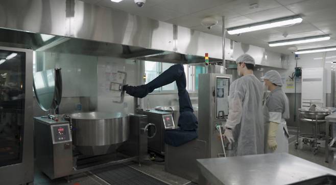 한 대형 급식 조리시설에서 관계자들이 조리 로봇이 음식을 만드는 과정을 지켜보고 있다. 강남구 제공