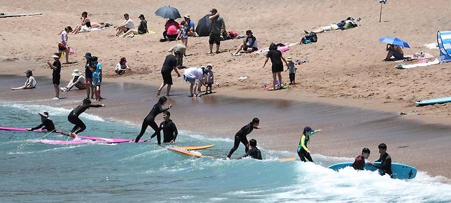 여름 날씨를 보인 이달 5일 제주 서귀포시 중문색달해수욕장에서 물놀이객이 서핑을 배우며 즐거운 시간을 보내고 있다. 뉴시스