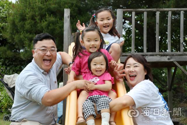 자녀 셋을 키우는 김종명·배정란 씨 부부가 집 마당에 미끄럼틀에서 놀고 있는 첫째 소민, 둘째 보민, 셋째 로아와 함께 행복한 미소를 짓고 있다. 정운철 기자 woon@imaeil.com