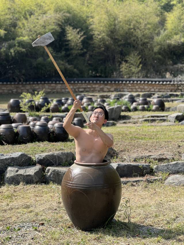 정확석 주무관이 상의를 벗고 옹기에 들어가 긴 도끼를 올려 든 채 울산옹기축제를 홍보하고 있다. 울주군청 제공