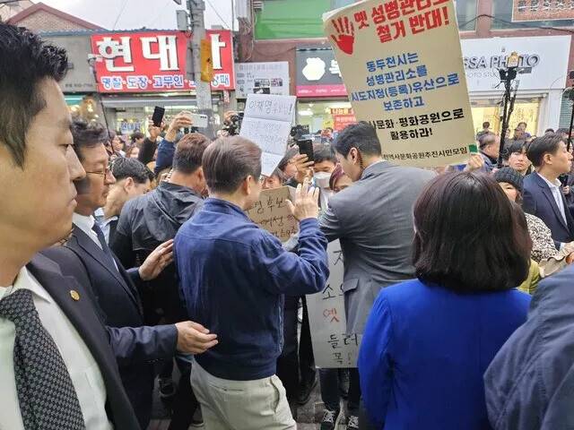 이재명 대통령이 후보 시절인 지난달 1일 오후 경기 연천군 전곡시장 일대를 지나던 중 동두천 옛 성병관리소 철거를 막아달라는 손팻말을 보고 있다. 김채운 기자
