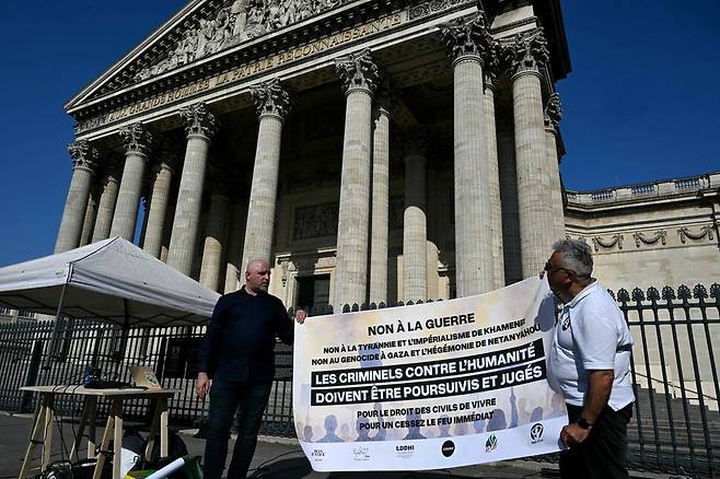 19일(현지시각) 프랑스 파리 판테온 광장에서 휴전을 촉구하는 시위대가 이란과 이스라엘 당국을 규탄하며 “전쟁 반대” 현수막을 들고 있다. 파리/AFP 연합뉴스