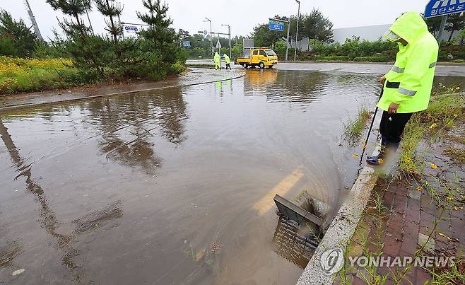 침수된 도로 (인천=연합뉴스) 임순석 기자 = 20일 인천 중구 운남동의 한 도로에서 인천시설공단 관계자들이 장맛비에 침수된 도로의 빗물받이에 쌓인 낙엽 등을 청소하고 있다. 2025.6.20 soonseok02@yna.co.kr