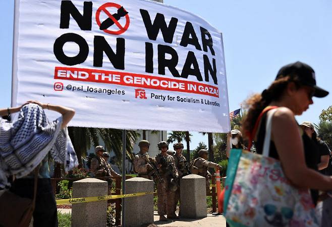 22일(현지시간) 미국 캘리포니아주 로스앤젤레스의 연방 청사 앞에서 시위대가 미국이 이스라엘과 함께 이란의 핵 시설을 공격한 데 대해 항의하는 시위를 벌이고 있는 가운데, 해병대원들이 경계를 서고 있다.(사진=로이터)