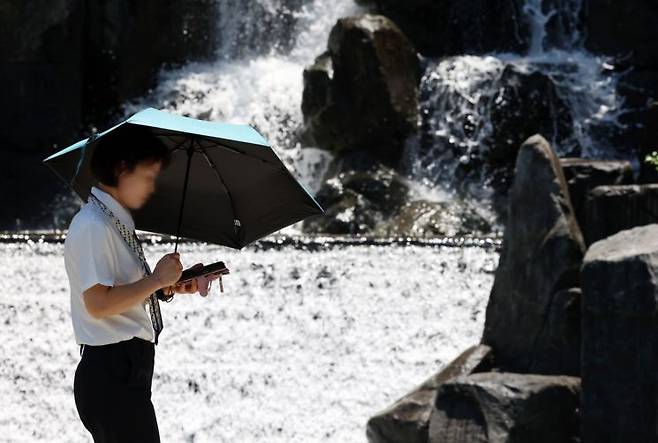 장마가 소강상태를 보인 23일 광주 서구 평화공원에서 한 시민이 강렬한 햇볕에 양산을 쓰고 걷고 있다. 연합뉴스