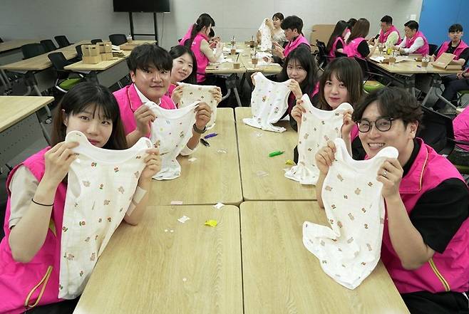지난 12일 서울 종로구 흥국생명 본사에서 임직원들이 미혼모 가정에 전달할 수면조끼 및 육아키트를 만든 뒤 기념 촬영을 하고 있다. 흥국생명 제공