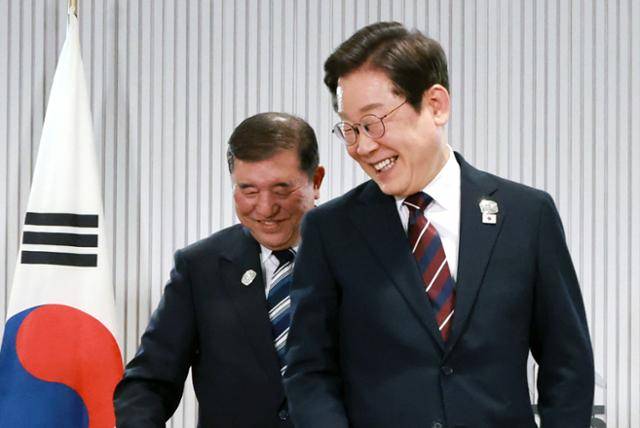 이재명 대통령이 지난 17일 캐나다 앨버타주 캐내내스키스 주요 7개국(G7) 정상회의장에서 열린 첫 한일 정상회담에서 이시바 시게루 일본 총리와 자리를 바꾸며 밝게 웃고 있다. 캐내내스키스=왕태석 선임기자