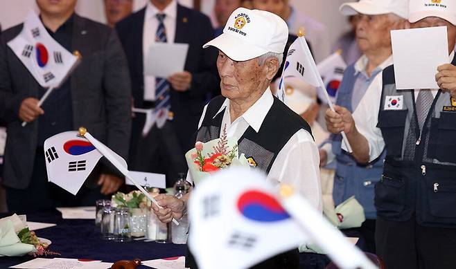 25일 경북 칠곡군의 한 웨딩홀에서 열린 참전용사 위안 행사에서 참전용사들이 태극기를 흔들며 6.25 노래를 부르고 있다. 연합뉴스