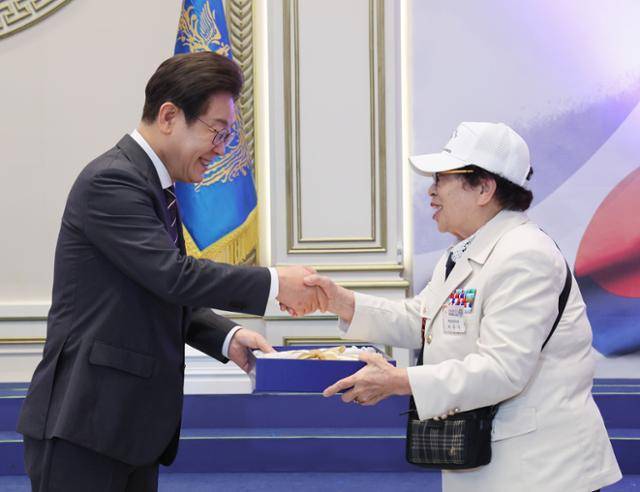 이재명 대통령이 27일 청와대 영빈관에서 열린 '호국보훈의 달, 대통령의 초대' 행사에서 특별초청 대상자인 6·25전쟁 참전유공자 이춘자 참전 용사에게 광목이불 선물을 전달하고 있다. 대통령실통신사진기자단