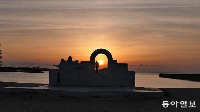 요론섬 서쪽 챠바나(茶花)해안에 서 있는 그리스 키클라데스 양식 하얀 구조물의 아치형 문으로 석양이 마지막 빛을 뿜어내고 있다.