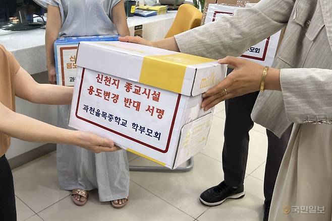과천시초중고학부모연합회 관계자가 이날 과천시청 관계자에게 반대 서명을 접수하고 있다.