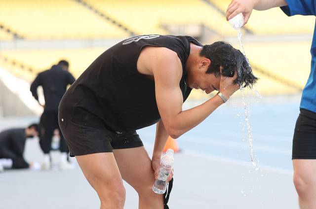 대구 낮 최고기온이 33.4도까지 오른 20일 대구스타디움에서 열린 대구시 재난안전기동대 채용 체력 검정을 마친 한 응시자가 시원한 물로 세수하고 있다. 연합뉴스
