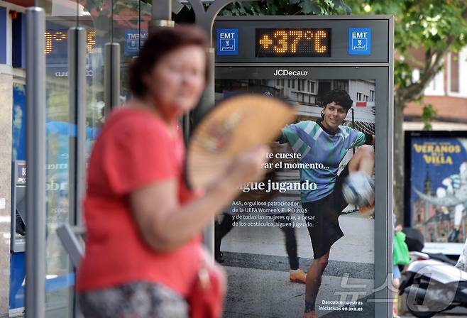 1일 스페인 마드리드 버스정류장에서 한 여성이 부채질을 하고 있다. 여성 뒤로 섭씨 37도의 기온이 표시돼 있다. ⓒ AFP=뉴스1