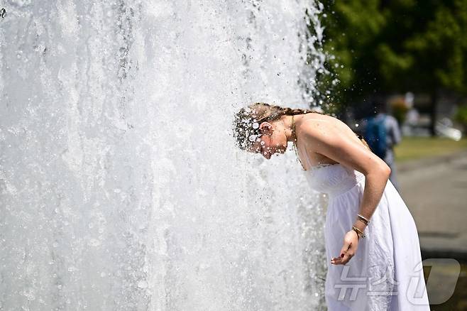 2일(현지시간) 독일 베를린의 한 공원에서 한 여성이 분수대 물에 머리를 적시고 있다. 2025.07.02. ⓒ AFP=뉴스1
