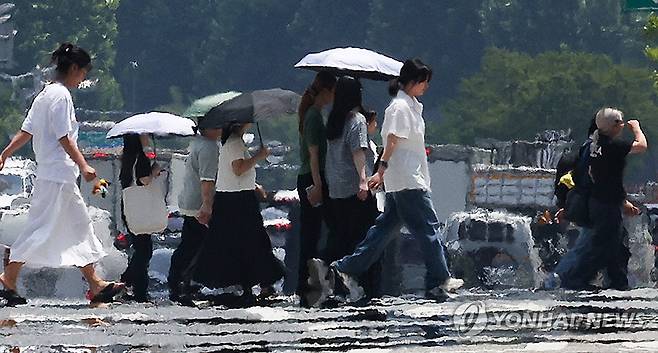 일주일째 폭염, 펄펄 끓는 도심 (대구=연합뉴스) 윤관식 기자 = 대구에 일주일째 폭염특보가 발효 중인 3일 대구 달서구 계명대학교 인근 도로에 지열로 인한 아지랑이가 피어오르는 가운데 시민들이 양산을 쓰고 이동하고 있다. 2025.7.3 psik@yna.co.kr