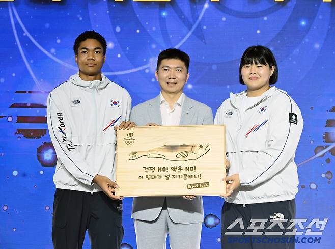 유승민 대한체육회장이 선수단의 액운을 막고 행운을 기원하는 마음을 담은 '액막이 명태' 기념품을 선수대표 나마디 조엘 진(육상), 김하윤(유도) 에게 전달하고 있다. 사진제공=대한체육회