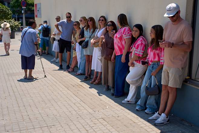 6월 30일 스페인 바르셀로나 사그라다 파밀리아 성당을 방문한 관광객들이 건물벽 그늘에 기대어서 더위를 식히고 있다./AP 연합뉴스