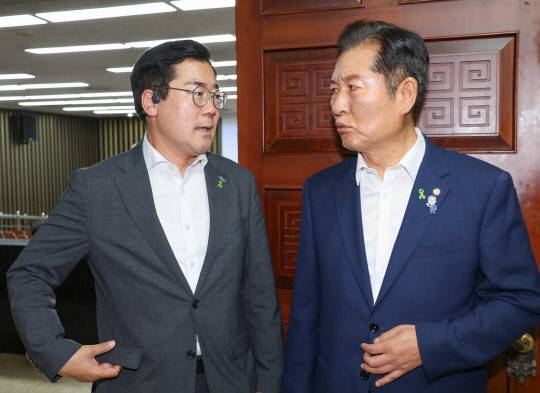 더불어민주당 당 대표 후보자인 정청래·박찬대(왼쪽) 의원이 3일 서울 여의도 국회에서 열린 비공개 의원총회장 앞에서 대화하고 있다. 연합뉴스