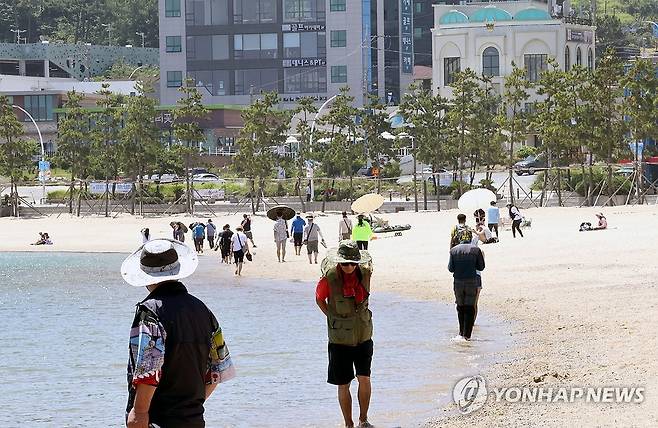 바다에서 더위 식히는 피서객들 (울산=연합뉴스) 장지현 기자 = 여드레째 폭염특보가 내려진 5일 오전 울산 동구 일산해수욕장을 찾은 피서객들이 바닷물에 발을 담그거나 해변을 거닐며 더위를 식히고 있다. 이날 울산의 낮 최고기온은 36도로 예보됐다. 2025.7.5 jjang23@yna.co.kr