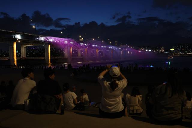 무더위에 열대야까지 겹친 1일 서울 서초구 반포한강공원을 찾은 시민들이 달빛무지개분수를 보며 더위를 식히고 있다. 연합뉴스