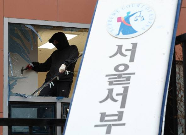 윤석열 대통령 구속 소식을 들은 일부 윤 대통령 지지자들이 불법폭력사태를 일으킨 서울 마포구 서울서부지방법원에서 한 작업자가 복구 작업을 하고 있다.(사진=연합뉴스)