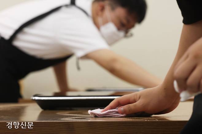 혜화 슬로우점에서 일하는 느린 학습자 청년들이 식탁을 닦고 있다.