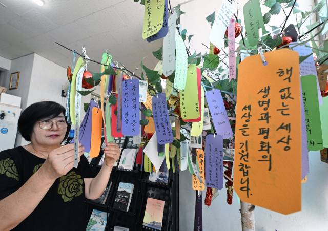 한정순 한국원폭피해자2세환우회 회장이 원폭2세 환우쉼터인 합천평화의 집에서 합천비핵평화대회 참가자들이 평화의 나무에 매단 소원지를 읽고 있다.