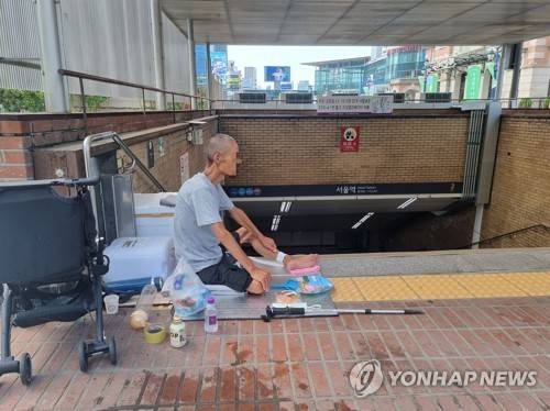 냉수로 버티는 더위 (서울=연합뉴스) 서윤호 인턴기자 = 9일 오전 서울역 2번 출구 앞에 노숙인이 앉아있다. 2025.7.9
