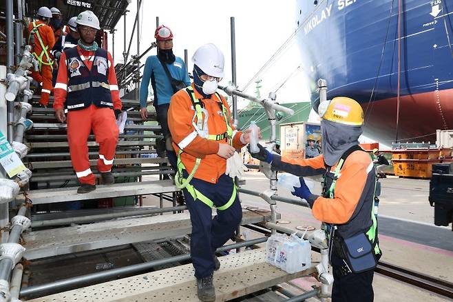 한화오션 안전관리자가 10일 '찾아가는 얼음생수' 활동으로 오후 쉬는 시간 작업자들에게 얼음 생수를 전달하고 있다. 한화오션 제공