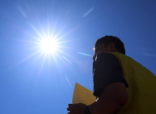 11일 서울 종로구 정부서울청사 앞에서 정부 규제개혁위원회(규개위)의 폭염 규칙 통과 촉구 기자회견을 하는 민주노총 조합원 위로 뙤약볕이 내리쬐고 있다. 연합뉴스