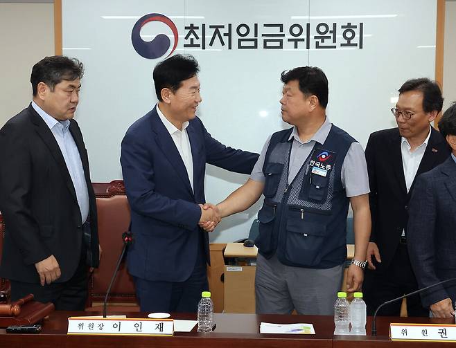 최저임금위원회 사용자위원 운영위원인 류기정 한국경영자총협회 전무(왼쪽 두 번째)와 근로자위원 운영위원인 류기섭 한국노총 사무총장(오른쪽 두 번째)이 10일 정부세종청사에서 열린 제12차 전원회의에서 내년 최저임금을 시간당 1만320원으로 17년 만에 합의로 결정한 뒤 악수하고 있다. 왼쪽은 이인재 위원장 ⓒ연합뉴스