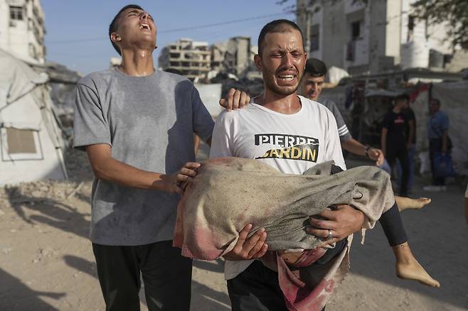 12일 한 팔레스타인인이 이스라엘군의 공습으로 숨진 어린이의 시신을 옮기고 있다. AP연합뉴스