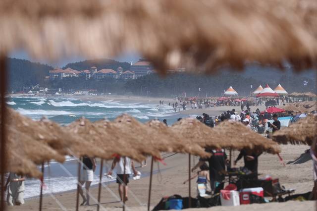 12일 강원 양양군 낙산해수욕장에서 피서객들이 밀짚 파라솔 밑에서 더위를 식히고 있다. 연합뉴스.