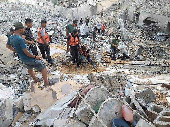 12일(현지시각) 가자 북부 가자시티에서 팔레스타인 민방위대원들이 무너진 건물 잔해 사이에서 피해자들을 수색, 구조하고 있다. 가자시티/UPI 연합뉴스