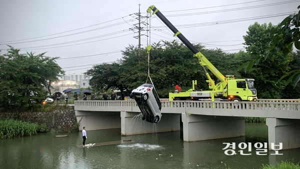 지난 14일 오후 7시40분께 수원시 권선구 황구지천에서 크레인 차량이 추락 차량을 인양하고 있다. 2025.7.14 /유혜연기자 pi@kyeongin.com