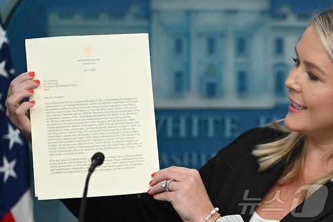 캐롤라인 레빗 백악관 대변인이 7일(현지시간) 미국 워싱턴 D.C. 백악관에서 열린 기자 회견에서 도널드 트럼프 미국 대통령이 이재명 대통령에게 보낸 관세 관련 서명 서한을 공개하고 있다. 트럼프 대통령은 이재명 대통령에게 보내는 서한에서 "불행히도 우리 관계는 상호적이지 않았다"면서 "2025년 8월 1일부터, 우리는 한국에서 미국으로 수출되는 모든 제품에 대해 품목별 관세와 별도로 25%의 관세를 부과할 것" 이라고 밝혔다. 2025.7.8 ⓒ AFP=뉴스1