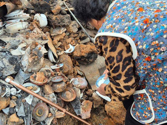 서복래 할머니가 4월 23일 안동 길안면 대곡1리 보초마을 집터 잔해 속 깨진 그릇 더미를 뒤지며 성한 그릇을 찾고 있다. 안동=김나연 기자