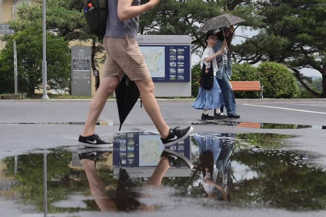 1일 경기 파주시 임진각에서 관광객들이 양산과 우산을 든 채 장맛비로 젖은 땅을 걷고 있다. 연합뉴스