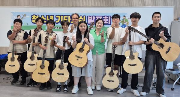 11일 의성읍온누리터에서 열린 청소년 기타교실 발표회에 참가한 학생들과 권정일 의성읍장(뒷줄 중앙), 김정화 강사(오른쪽 네번째) 지역사회보장협의체 관계자들이 기타를 들고 기념 촬영을 하고 있다. 의성군