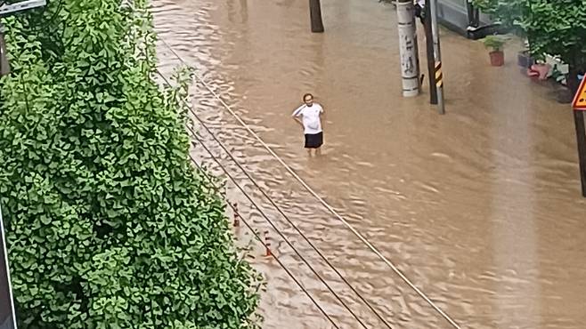 17일 오후 광주 북구 중흥동의 한 도로가 물에 잠겨 도로 유도선이 보이지 않자 인근 시민이 차량통제를 하고 있다. 독자 제공