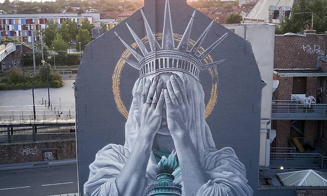 프랑스 북부에 있는 이민자 도시 루베의 어느 건물 외벽에 미국 뉴욕 자유의 여신상을 패러디한 대형 벽화가 그려져 있다. 자유의 여신이 양손을 들어 두 눈을 가리고 있는 모습이다. AP연합뉴스