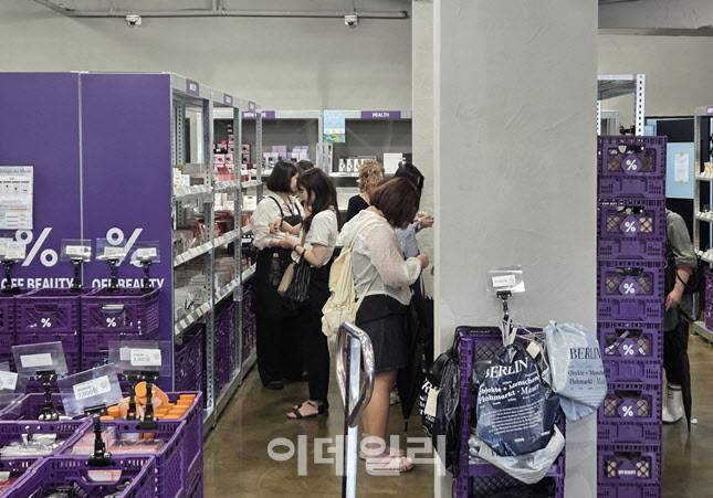 오프뷰티 광장시장점 매장에서 외국인 관광객과 20~30대 소비자들이 할인 화장품을 고르고 있다. 창고형 인테리어와 보라색 큐레이션 박스가 매장 곳곳에 배치돼 있다. (사진=한전진 기자)