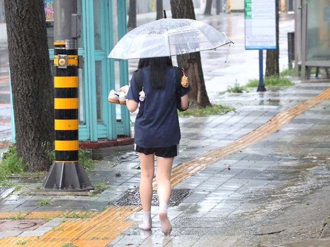 천둥·번개를 동반한 강한 비가 내리던 지난 11일 광주 남구 월산동 한 중학교 앞에서 한 학생이 빗속에 신발을 들고 걸어가고 있다. 뉴스1