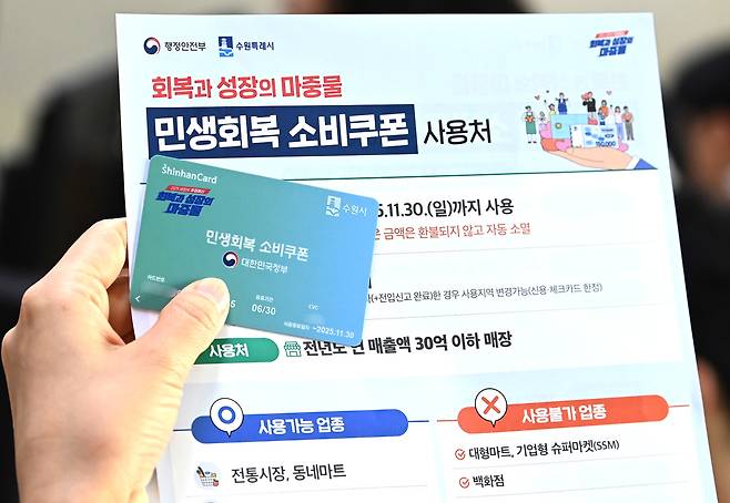 정부의 민생회복 소비쿠폰 1차 신청 첫날인 21일 경기 수원시 행궁동 행정복지센터에서 한 시민이 선불카드를 수령받고 있다. 뉴시스