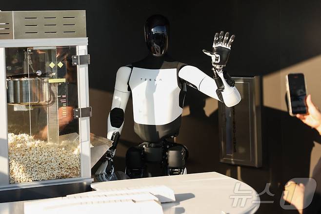 21일(현지시간) 미국 로스엔젤레스에서 테슬라 다이너 앤 드라이브인 레스토랑과 슈퍼차저 개장식에서 테슬라 옵티머스 로봇이 시민들을 향해 손을 흔들고 있다. ⓒ AFP=뉴스1