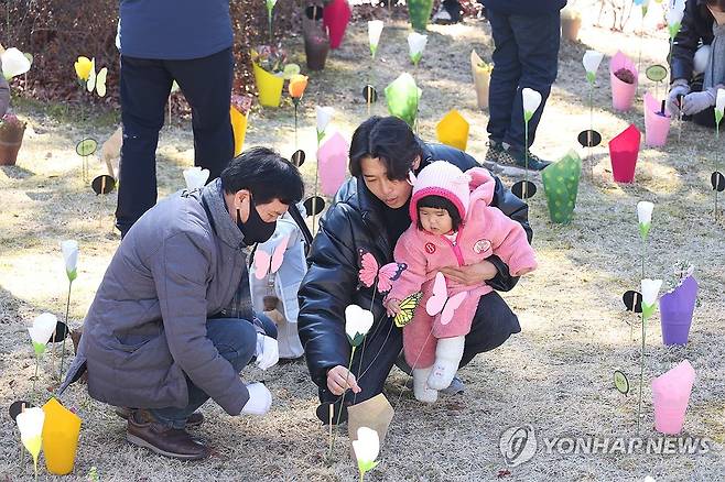 '고모, 안녕' (대구=연합뉴스) 박세진 기자 = 대구지하철참사 22주기인 지난 2월 18일 대구 동구 대구시민안전테마파크에서 열린 추모식에서 희생자의 한돌 지난 조카를 비롯한 유족들이 희생자를 기리는 꽃을 놓으며 추모하고 있다. 2025.2.18 psjpsj@yna.co.kr