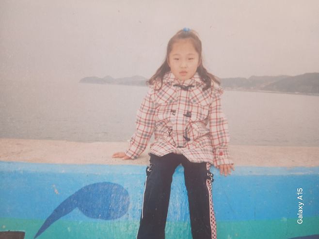 어릴 적 홍수연씨가 바닷가 앞에 앉아 있다. 홍순성씨 제공