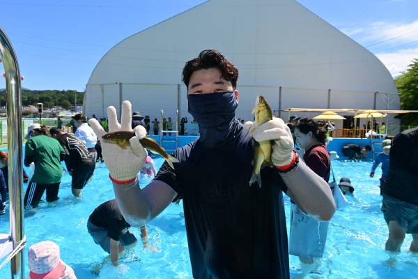 은어 맨손잡이 체험장에서 참가자한 관광객이 은어를 잡아 들어 보이며 즐거운 표정을 짓고 있다.
